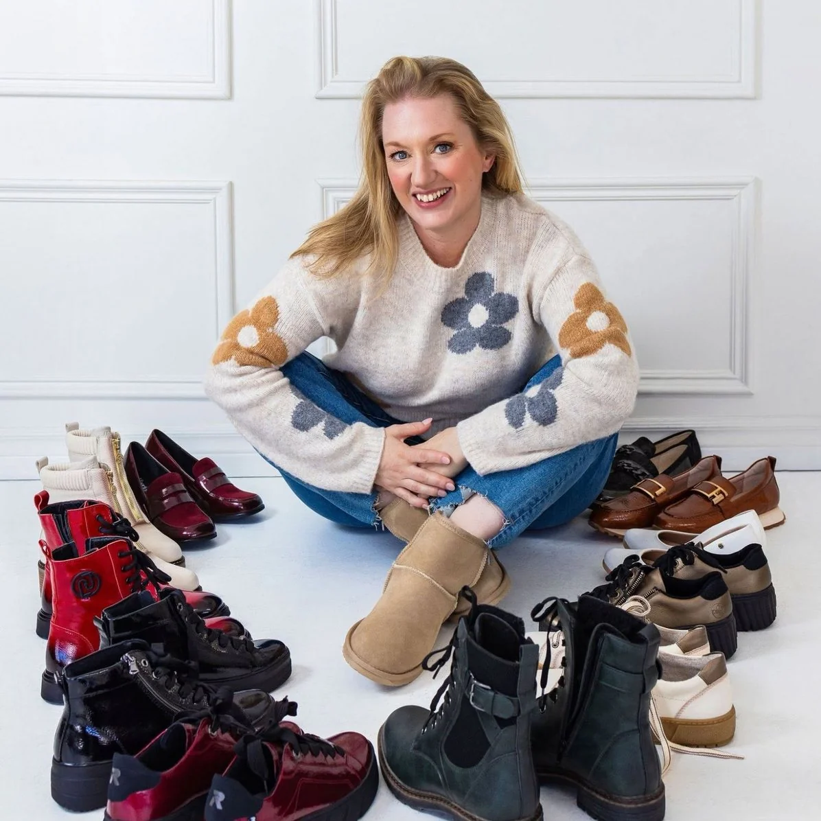 Claudine Péclet, propriétaire d’Escarpins et Vilebrequins, assise par terre parmi les bottes et les chaussures de sa boutique.